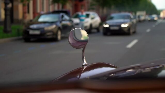Retro old vintage red car driving in a city road in sunny summer day. Rear view mirror and hood.