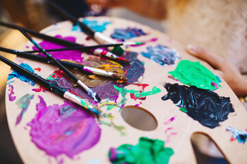 A paint palette full of colors and brushes.