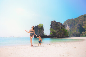 Obraz premium Boy and his mother are strolling along the beach, admiring the stunningly bright blue waters of Krabi, Thailand