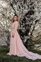 Obraz na płótnie Canvas A beautiful woman in a spring garden near cherry blossoms. Flowering garden