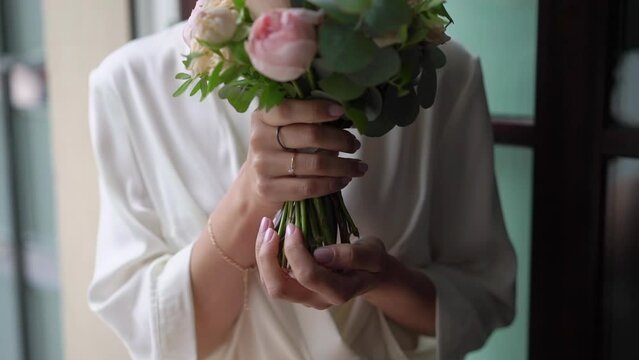Female in dress hold in hands bouquet with ribbons oof white and pink rose peony flowers. Gift for a woman, holiday, wedding bouquet of the bride. Floristics.