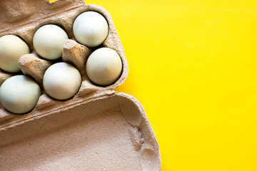 Lots of white chicken eggs on a yellow shelf background. A source of protein for health, ingredients for a quick breakfast for dieting, losing weight and athletic people.
