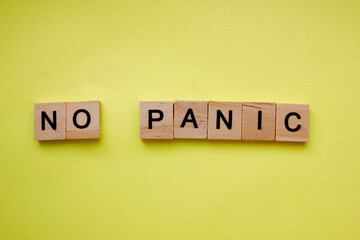 Word not panic on a yellow background. The inscription is made of wooden cubes. Danger, panic. A Call to Remain Calm. Copy space. Top view. Flat lay