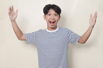 Fun portrait of a young Asian man looking dumbfounded and open mouth on isolated background