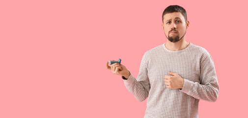 Confused man with inhaler on pink background with space for text