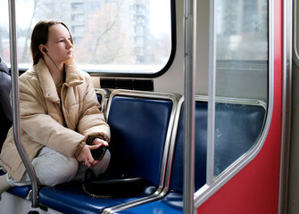 young girl teenager rides in transport looks out the window headphone mobile phone peaceful face space for text Sky Train bus car ordinary person in real life street Cities canada suburb surrey