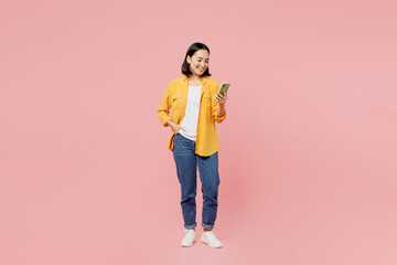 Full body young woman of Asian ethnicity wear yellow shirt white t-shirt stand hold in hand use...