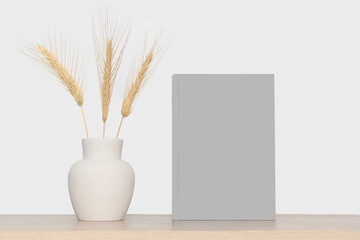 Mock-up of a gray book and a gray vase with dry branches of wheat.