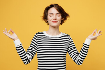 Young spiritual tranquil woman wear casual striped black and white shirt hold spreading hands in...