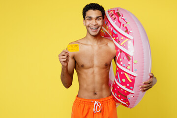 Young man in orange shorts swimsuit relax near hotel pool hold rubber donut ring hold in hand mock...