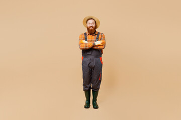 Full body young bearded man wears straw hat overalls gumboots work in garden look camera hold hands...