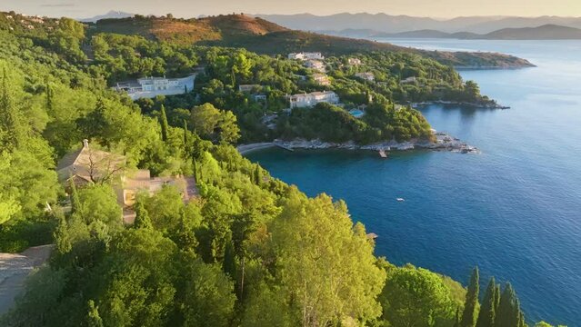Flying over lush green vegetation, villas and sea bays on Corfu island. Gorgeous mediterranean landscape of Corfu island, Greece. Tourism landmark romantic honeymoon travel destination. Aerial shot