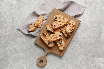 Wooden board with tasty biscotti cookies on grunge background