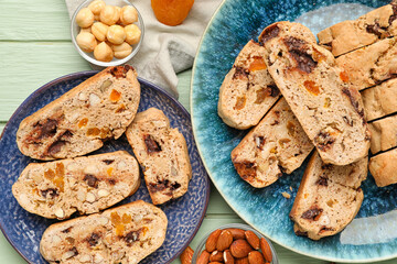 Plates with tasty biscotti cookies and nuts on color wooden table, closeup