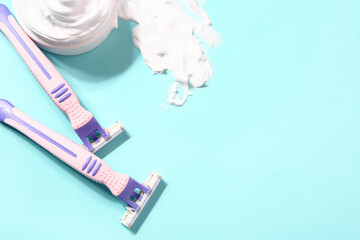 Safety razors and shaving foam on color background