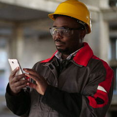 African american workman with smartphone at construction site