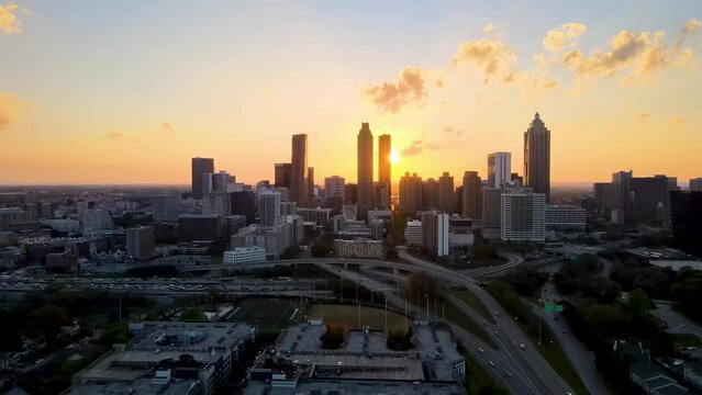 aerial drone footage of Atlanta downtown metropolis skyscraper  during sunsets. the bright orange sun goes down between the building architectures related to urban travel, vacations and traffic 