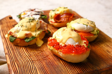 Board with different eggs Benedict on table, closeup