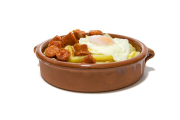 Chistorra with fried potatoes and fried eggs, served in a clay bowl (Chistorra, is a type of sausage of Navarre origin made with fresh minced pork.Isolated in a white background. Spanish food concept.