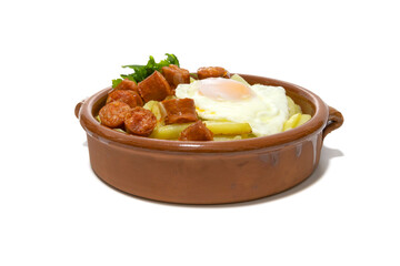 Chistorra with fried potatoes and fried eggs, served in a clay bowl (Chistorra, is a type of sausage of Navarre origin made with fresh minced pork.Isolated in a white background. Spanish food concept.