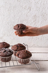Woman holding tasty chocolate cupcake at table