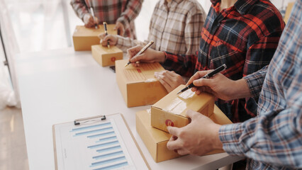 Team of smes warehouse checking email and writing on parcel cardboard box, Small business entrepreneur, SME, freelance online sellers, influencer and the team behind the work.