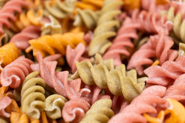 Rice vegetable pasta in the form of spirals, top view. Healthy rice pasta with tomatoes, celery, carrots and beets
