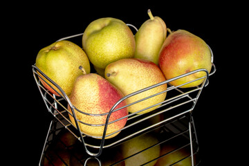 Several delicious tasty pears in a metal basket, close-up, on a black background.