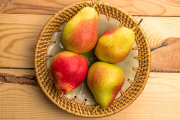 Four sweet juicy pears in a  plate, close-up, on a wooden table, top view.