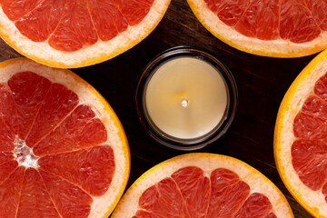 Soy candle in a jar top view. Citrus fruit grapefruit cut. Aromatherapy. Aroma candle aesthetic...