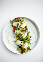 zucchini and arugula rolls on a white plate