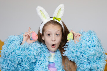 Happy easter! Portrait of funny happy laughing child girl with easter eggs and bunny ears on white background. funny wow face.