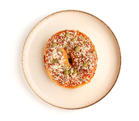 Plate of tasty bagel with sesame and pumpkin seeds on white background