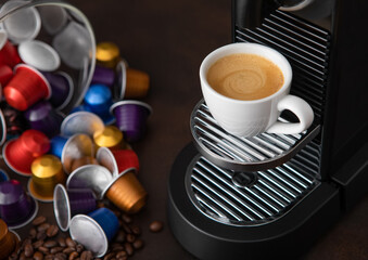 White cup with hot aroma coffee from espresso machine pods on dark background.