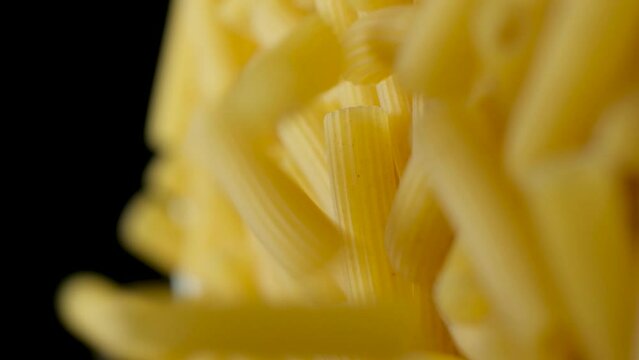 Flying wheat pasta Rigatoni in the form of tubes fall from top to bottom, close-up, slow motion shooting.