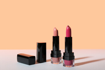 Beautiful lipsticks on table against color background