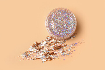 Jar of glitter on beige background, closeup