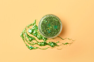 Jar of green glitter on beige background, closeup