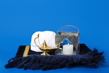 Muslim lantern with Aladdin lamp, hat and mat on blue background