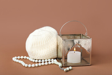Muslim lamp with burning candle, prayer beads and hat on brown background
