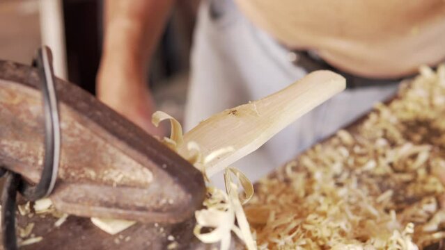 detail shot of man's hand carving wooden spoon in the patio of his house in colombia