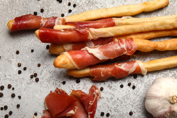 Tasty Italian Grissini with bacon on light background, closeup