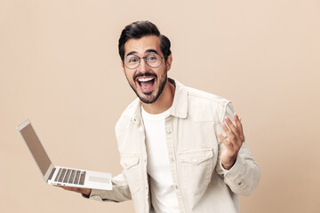 Portrait of a stylish with a laptop in his hands mockup, working freelancer smile with teeth open mouth slavery victory, beige background in a white t-shirt, fashionable clothing style, space space 