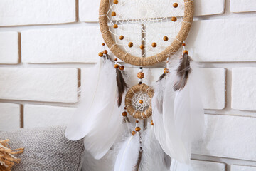 Dream catcher hanging on white brick wall in room, closeup