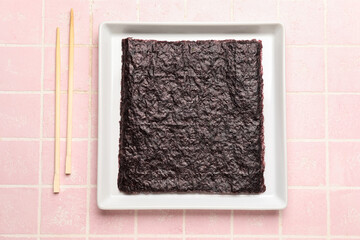 Plate with nori sheets on pink tile background