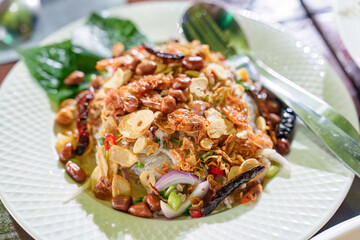Spicy vermicelli salad with meat and herb on ceramic plate