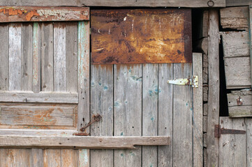 The wall of an old wooden barn built from scrap materials. The texture of old boards. 