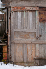 An old pitchfork with a wooden handle near a wooden barn.