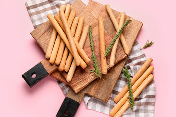 Wooden boards with tasty Italian Grissini on pink background