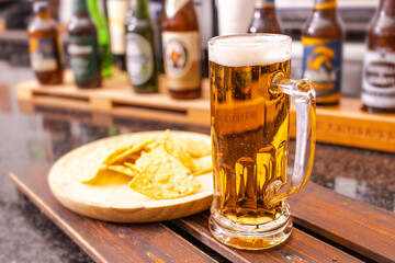 Glass of beer on wooden board and blurred bar background.Free space for your decoration.